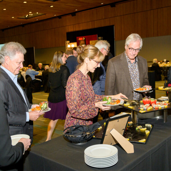 Guests serving themselves at the sushi food station at the 2023 Laughs + Libations event.