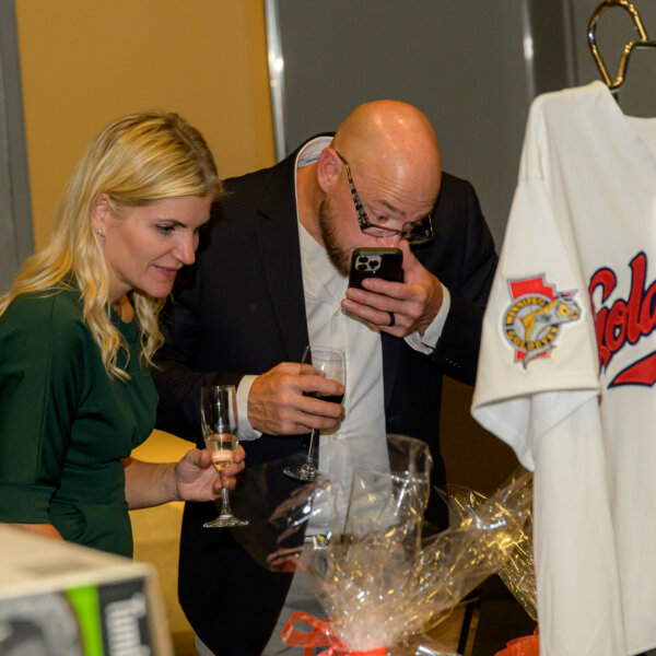 A couple browses the silent auction items at the 2023 Laughs + Libations event.