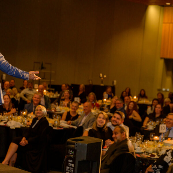 Comedian performing in front of a smiling crowd at the 2023 Laughs + Libations event.