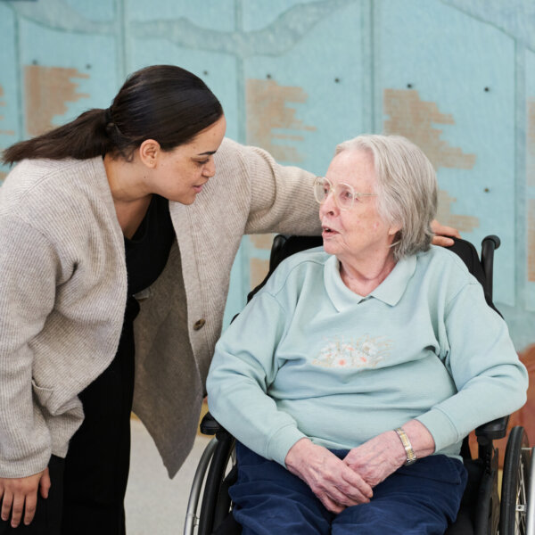 A Therapeutic Recreation Facilitator talks with a resident in a wheelchair.