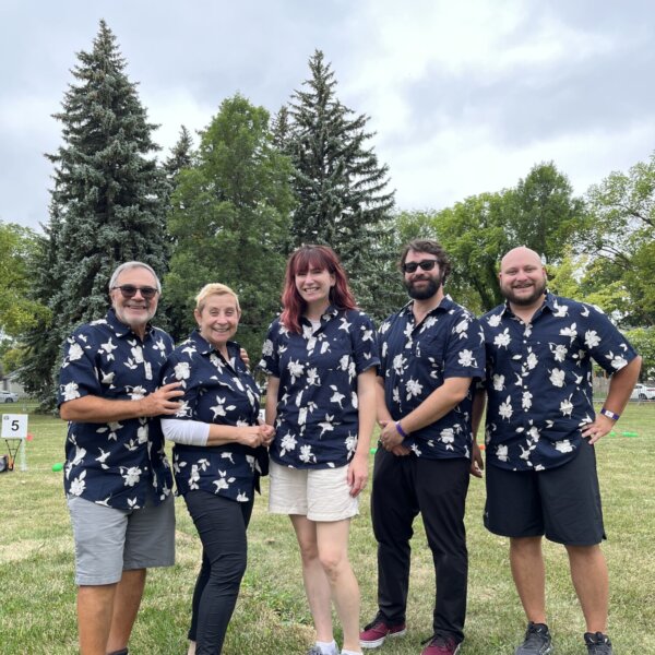 A team wearing matching navy floral shirts pose for a photo.