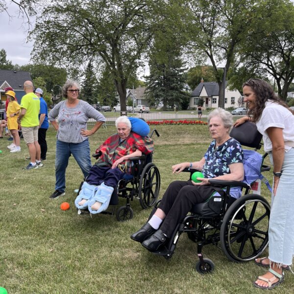 A resident in a wheelchair throws a green ball. Other games are visible in the background.