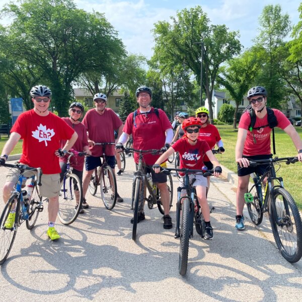 Seven cyclists wearing red pose for a photo on the RHC grounds.
